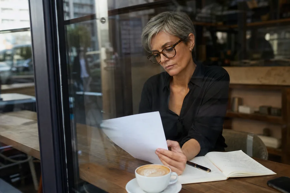 Independent consultant reading a retainer agreement at a cafe window table